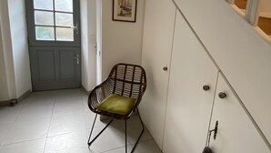 Una habitació amb una porta, una cadira, un quadre penjat a la paret i una escala.