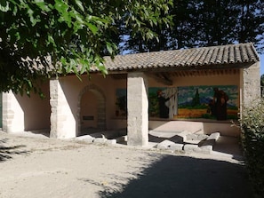 A building with a tiled roof, stone columns, and a mural on the wall.
