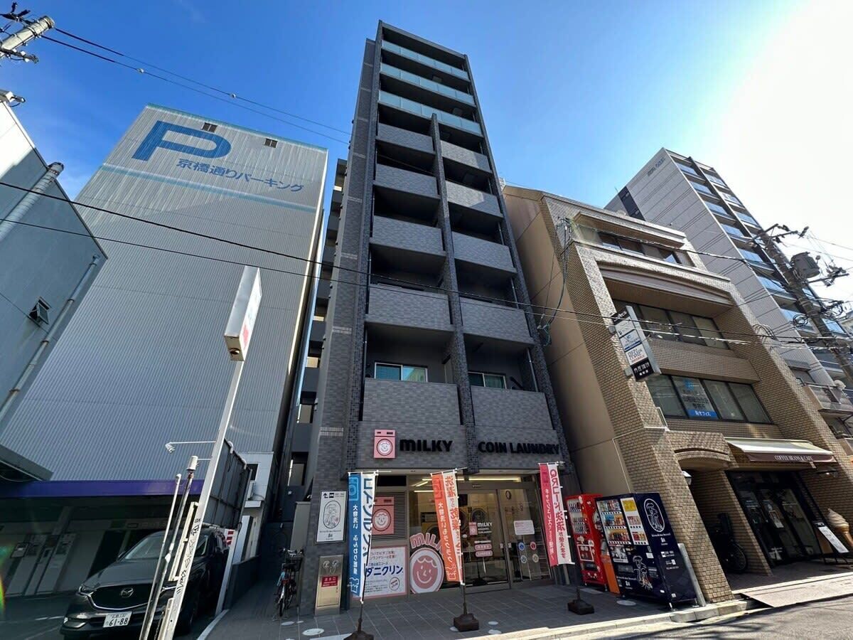 A multi-story building with a parking sign, a coin laundry, and various commercial establishments.