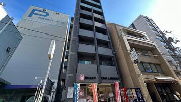 A multi-story building with a parking sign, a coin laundry, and various commercial establishments.