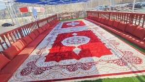 Un espace extérieur abrité, doté d’un tapis rouge et de sièges.
