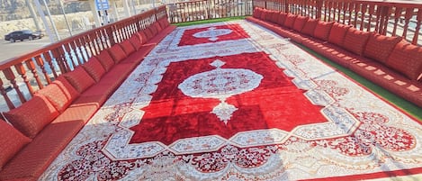 A covered outdoor area with a red carpet and seating.
