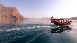 Un bateau sur une étendue d’eau calme, avec une chaîne de montagnes en arrière-plan.