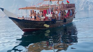 Un bateau en bois traditionnel, avec des passagers à bord, une cabine et un auvent.