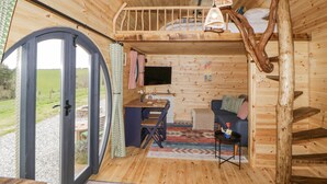 A cozy cabin interior with a wooden interior, a dining area, a sofa, and a television.