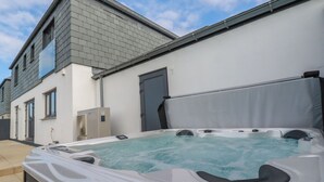 A hot tub in front of a modern house with a grey roof and white walls. - Lavender House (Newquay)