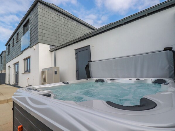 Ein Whirlpool vor einem modernen Haus mit grauem Dach und weißen Wänden.