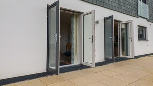 Un edificio moderno con tres puertas de vidrio que dan a un espacio exterior techado.