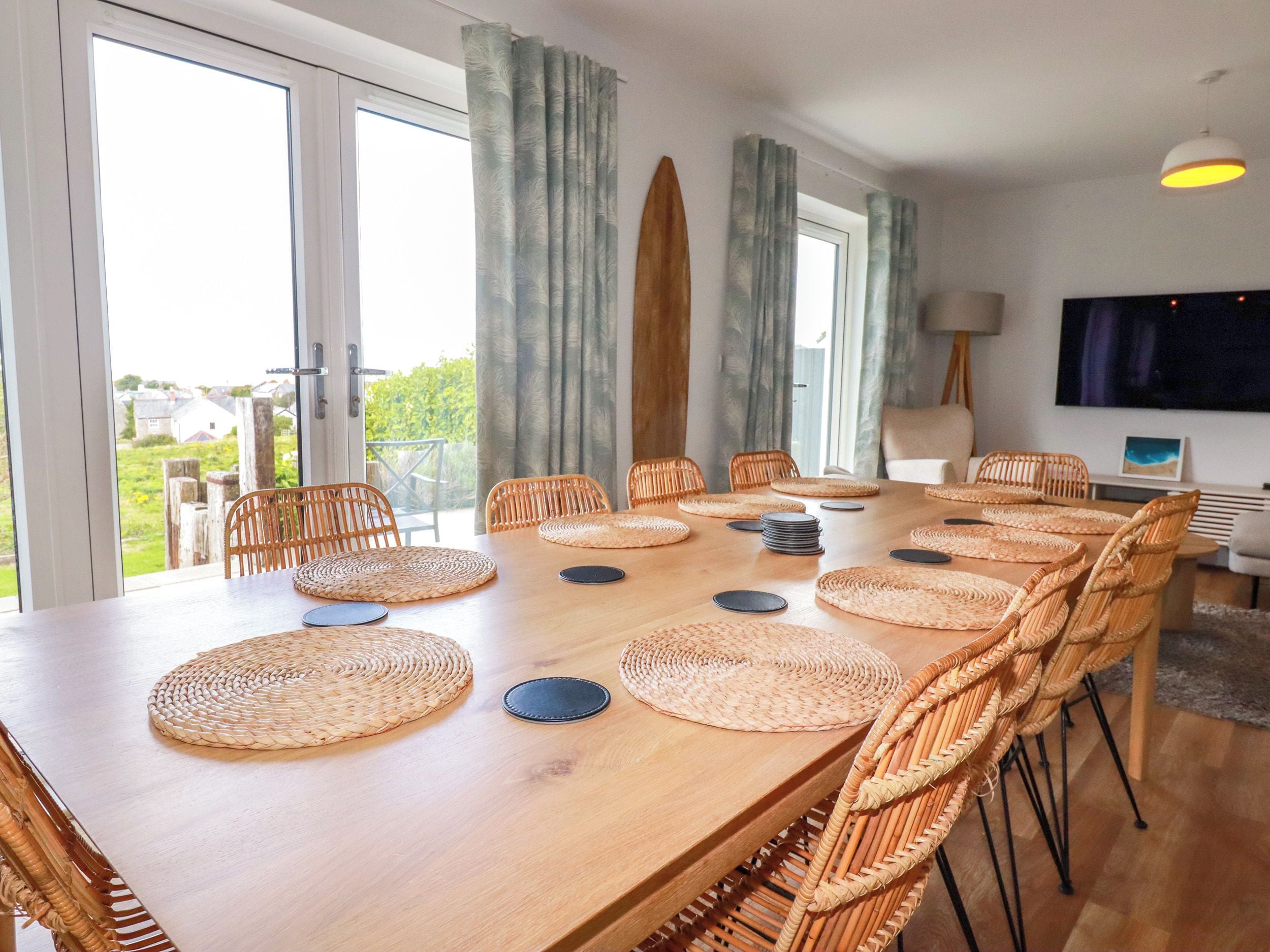 Un comedor con una larga mesa de madera, sillas de mimbre y individuales tejidos.