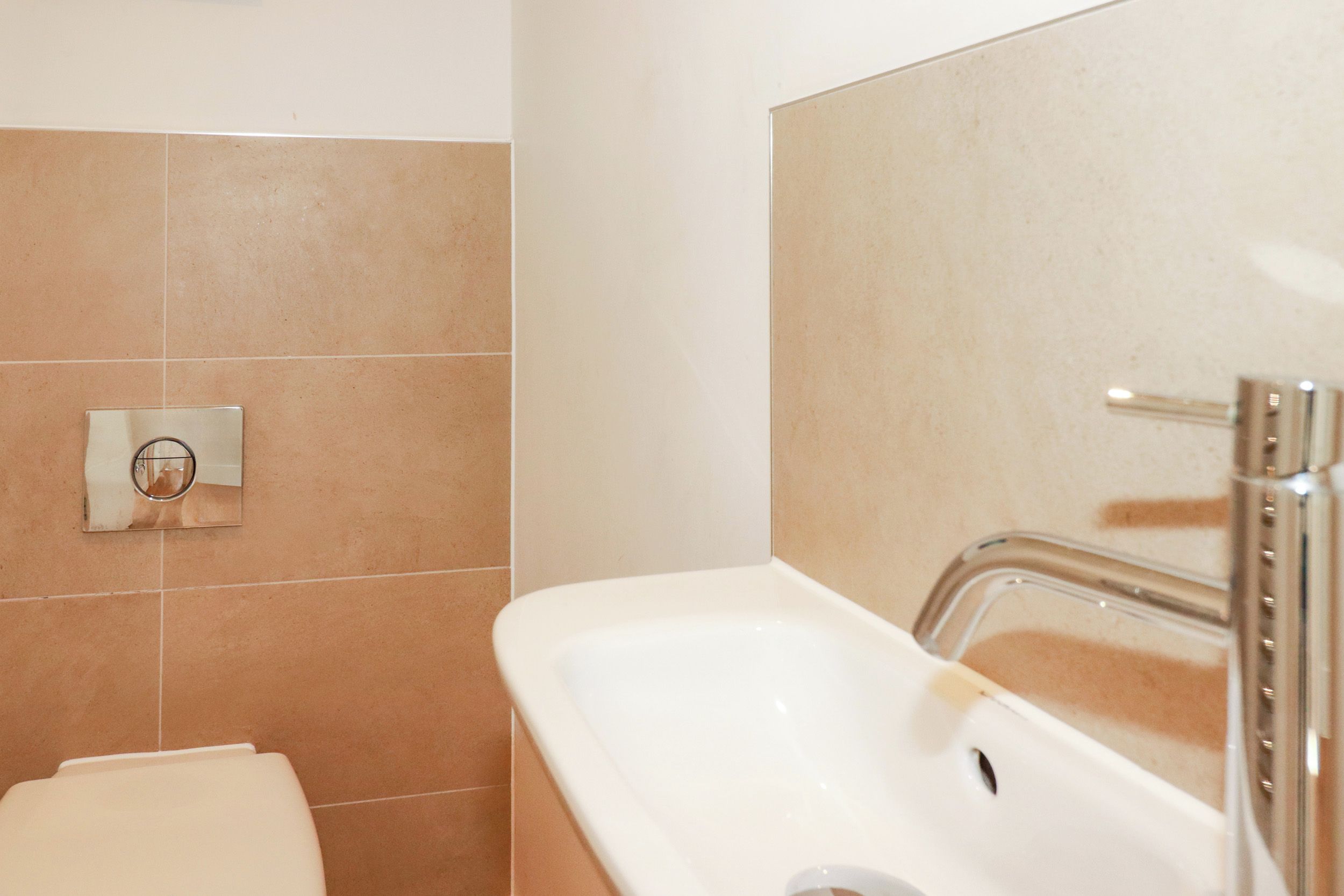 A bathroom with a white sink, a mirror, and a wall-mounted faucet.