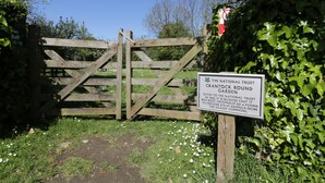 Una puerta de madera con un cartel que indica Jardín Crantock Trust.