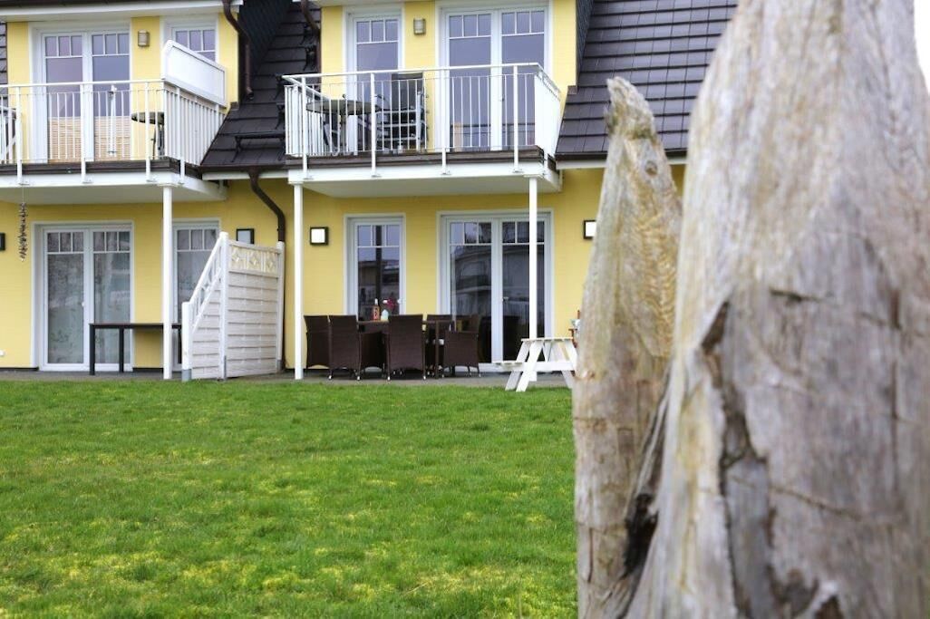 A two-story building with a balcony, a staircase, and a grassy yard.