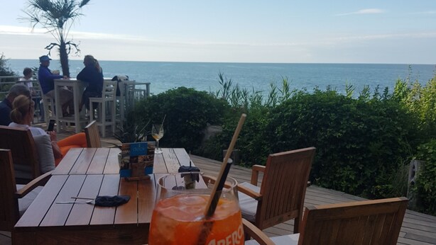 En træterrasse med et bord, stole og et glas Aperol.