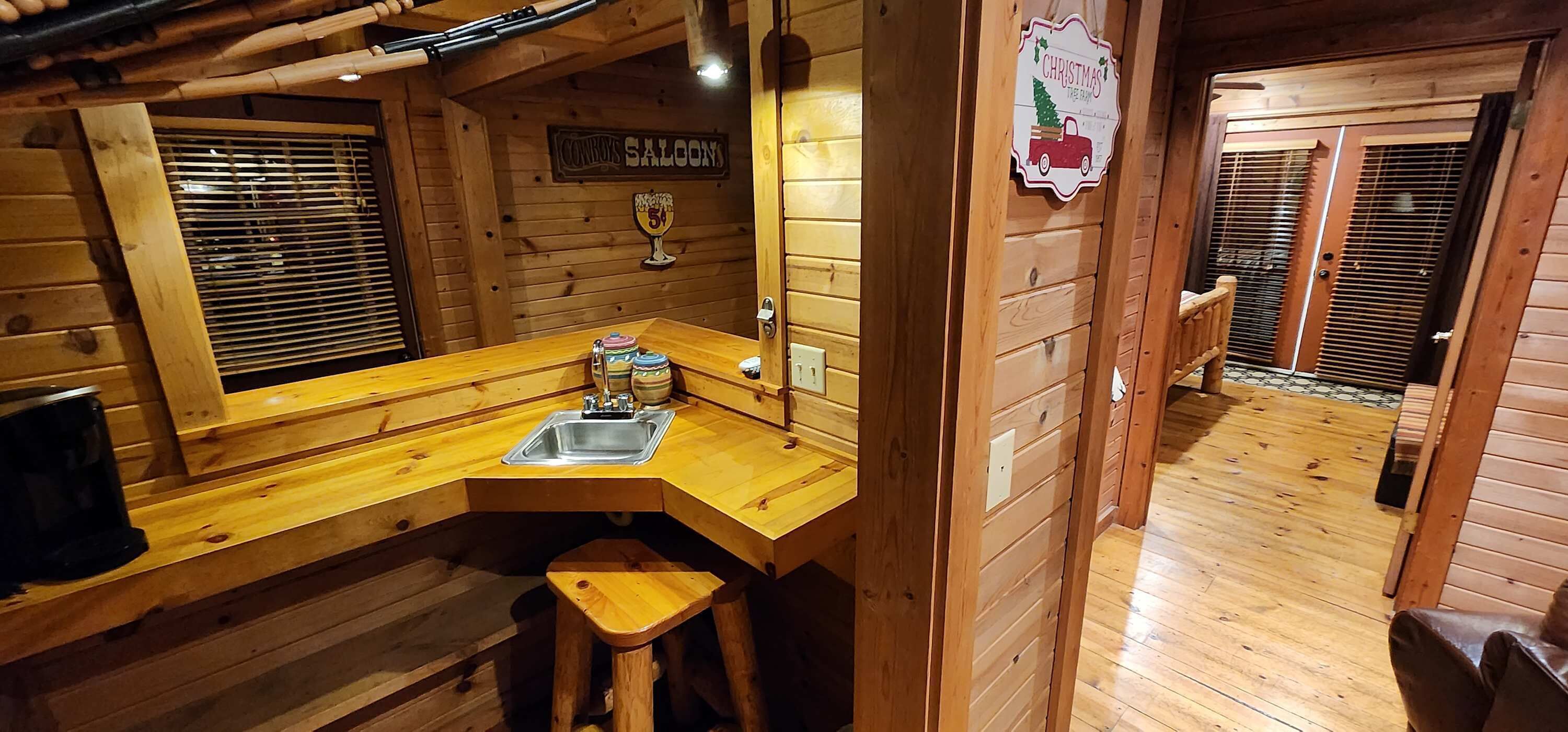 A wooden interior with a bar area, a sink, and a Christmas sign.