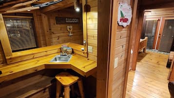 A wooden interior with a bar area, a sink, and a Christmas sign.