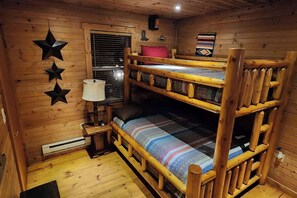 A cozy cabin with a bunk bed, wooden walls, a small table with a lamp, and star decorations.