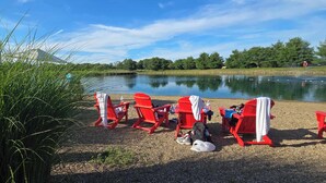Uferlage mit roten Adirondack-Stühlen, einem Kiesweg und einem ruhigen See.