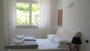 Une chambre à coucher avec un lit, une fenêtre avec des rideaux, une lampe de chevet et un interrupteur fixé au mur.