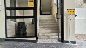 A building entrance with a tiled floor, a staircase, and a hand sanitizer dispenser. - BERILO DELUXE APARTAHOTEL (Barranquilla)
