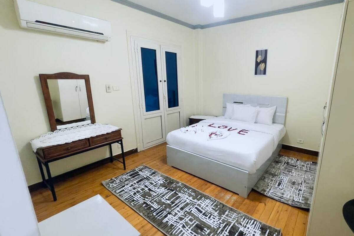 A bedroom with a bed, a dresser, a mirror, and a door.