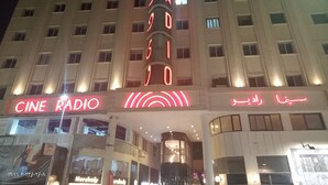 En byggnad med flera våningar, där det på bottenvåningen finns en stor, väl synlig skylt med texten ”Cine Radio”.