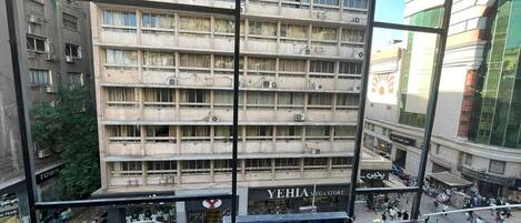 Un edificio de varios pisos con balcones y una tienda visible llamada "YEHI ANA MEGA STORE", con una calle concurrida abajo.