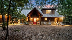 A rustic cabin with a prominent front porch, stone steps, and multiple seating areas. - Close to All~Mini Golf~Fire-Pit~Swing Set~Hot Tub (Broken Bow)