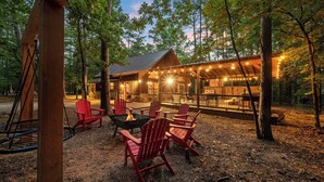A rustic cabin with a fire pit and red Adirondack chairs in a wooded area. - Close to All~Mini Golf~Fire-Pit~Swing Set~Hot Tub (Broken Bow)