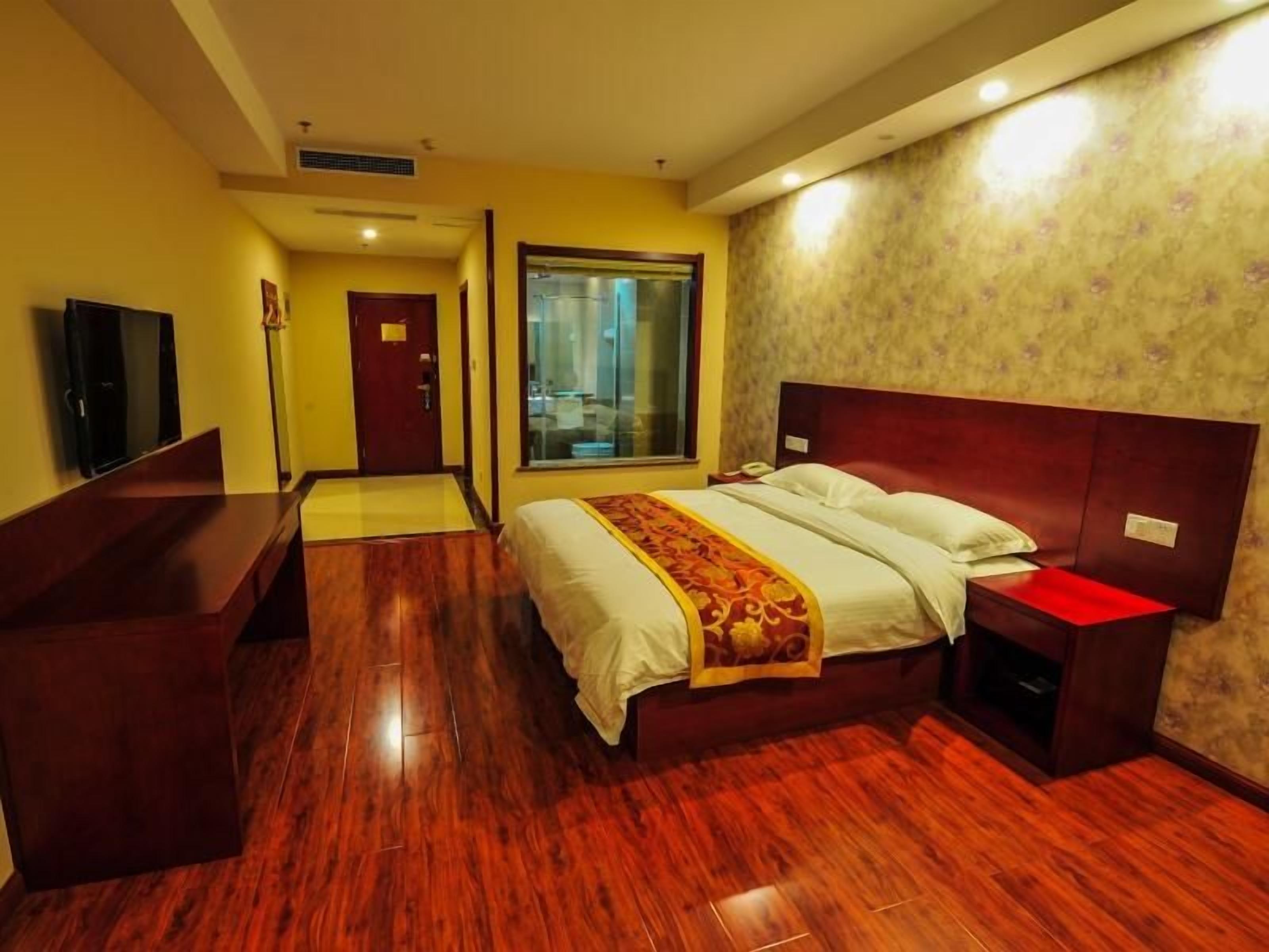 Een hotelkamer met een groot bed, een bureau, een televisie en een raam.