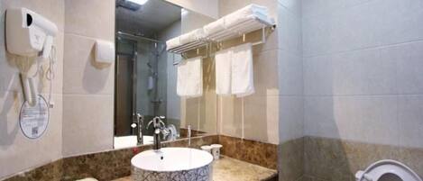 Ein Badezimmer mit einem runden Waschbecken, einem Spiegel, einem Handtuchhalter und einer Toilette.