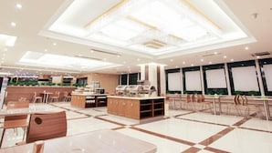 Un restaurant spacieux au design moderne, doté d’un îlot central, de plusieurs espaces de détente et d’un luminaire décoratif au plafond.