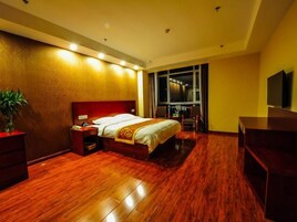 Habitación de hotel con una cama grande, un escritorio, una silla, un televisor y una ventana con vistas.