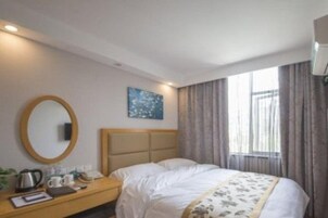Una habitación de hotel con una cama, una mesita de noche con lámpara, un espejo y una ventana con cortinas.