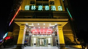 L’entrée d’un hôtel, avec une enseigne en caractères chinois, une porte vitrée et une façade bien éclairée.