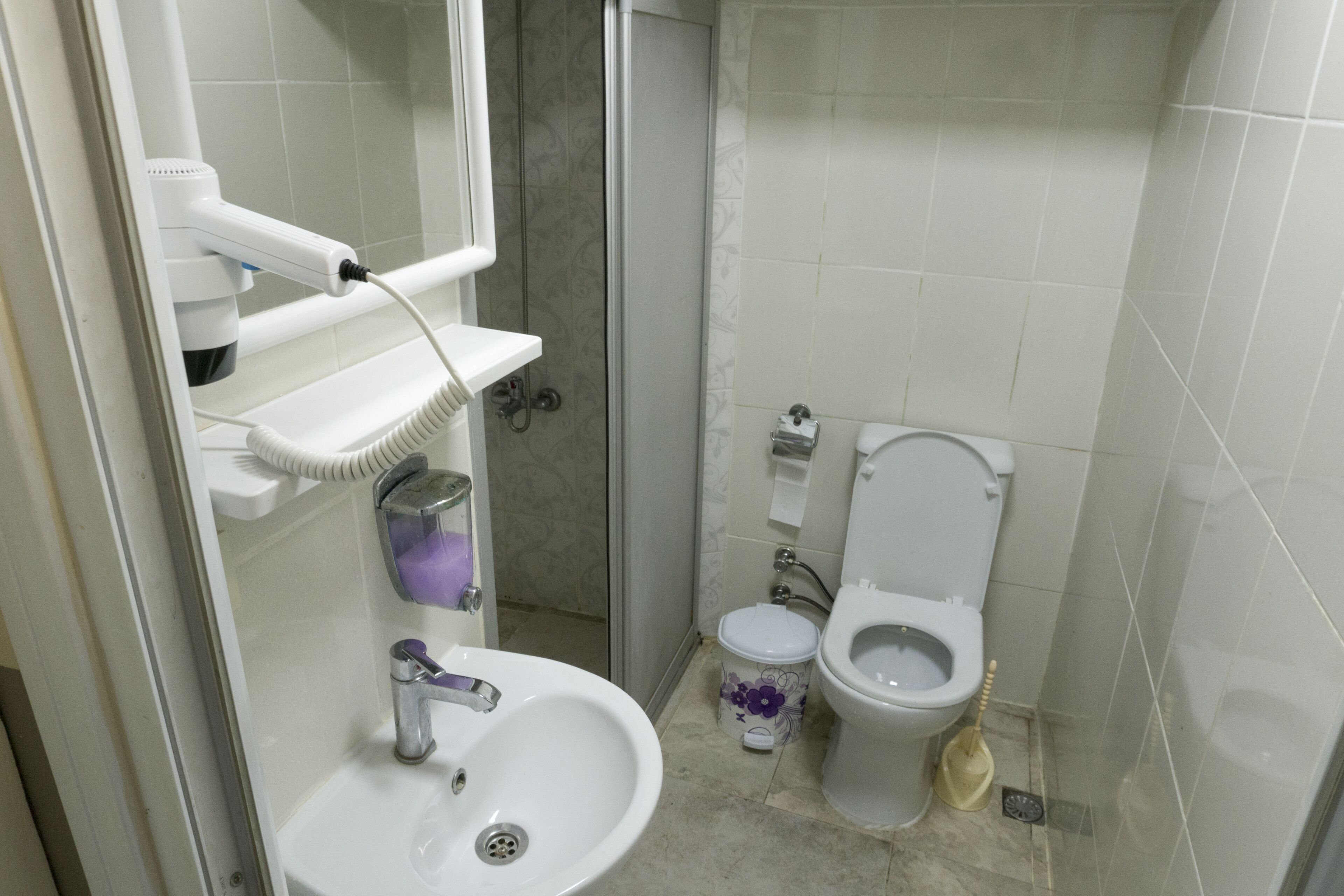 Un baño con lavamanos, dos inodoros, ducha y espejo.