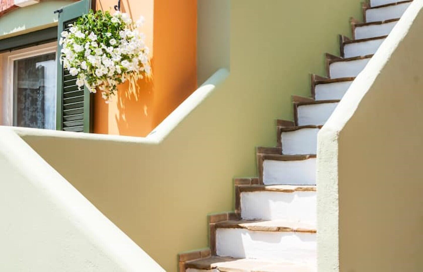 A staircase with white steps and a hanging flower basket.