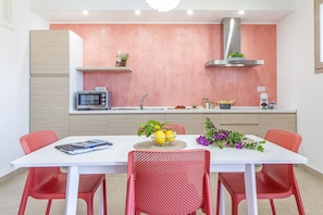 A modern kitchen with a white countertop, a built-in microwave, and a stainless steel range hood. - Skyfive Fire, Ideal for those who love a carefree holiday. Relaxation and amazement (Alghero)