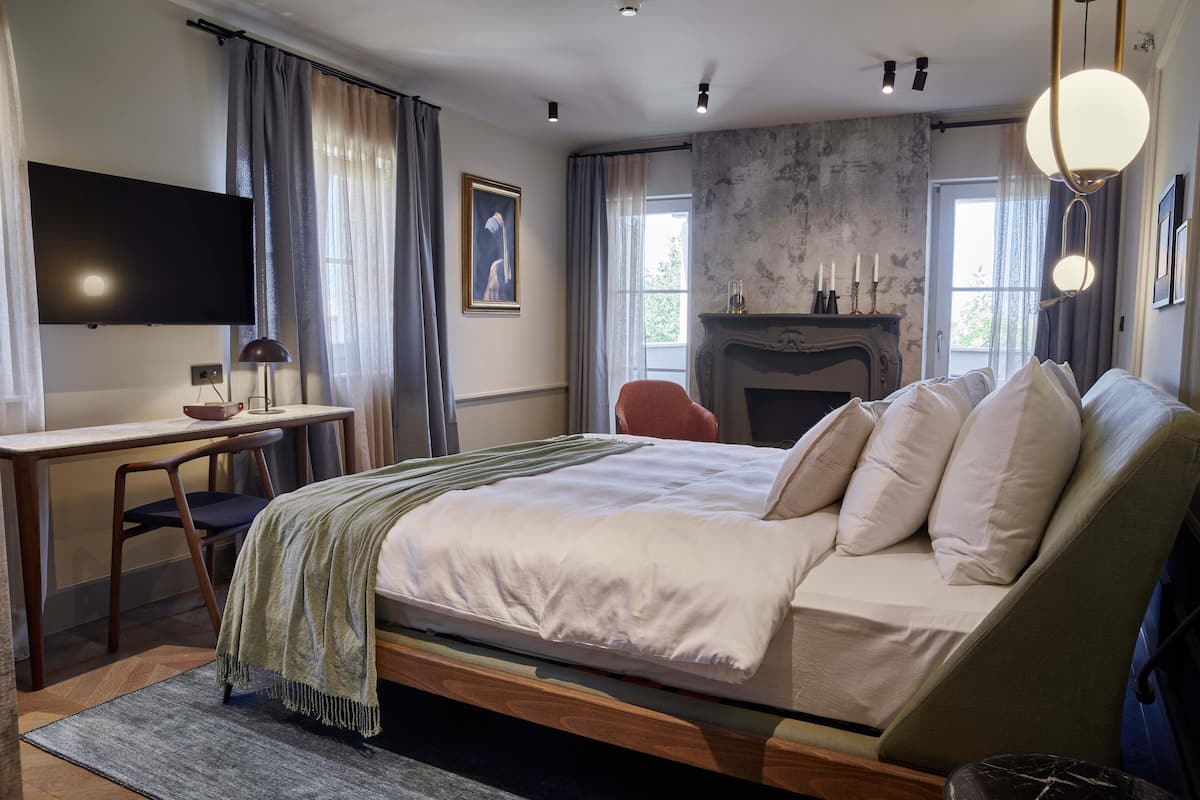 Une chambre moderne avec un grand lit, un bureau, une chaise, une télévision et une cheminée.