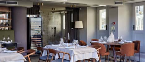 Ein Restaurant mit gedeckten Tischen, einer Bar und einem großen Fenster mit Blick.