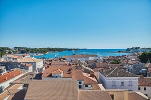 Un pueblo costero con edificios de tejados terracota, un puerto deportivo y un cielo azul despejado.