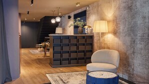 Um interior moderno com um sofá, um banquinho azul, uma luminária e uma estante de livros.
