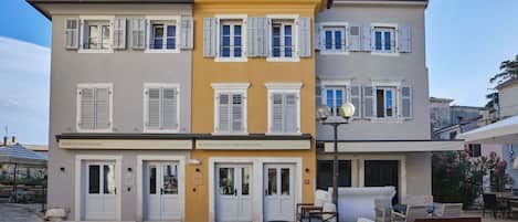 Un edificio de dos pisos con fachada amarilla y contraventanas blancas. Tiene un letrero que dice 'Martis Restaurant' y 'Martis Forum Heritage Hotel'. Hay áreas de estar al aire libre con mesas y sillas.