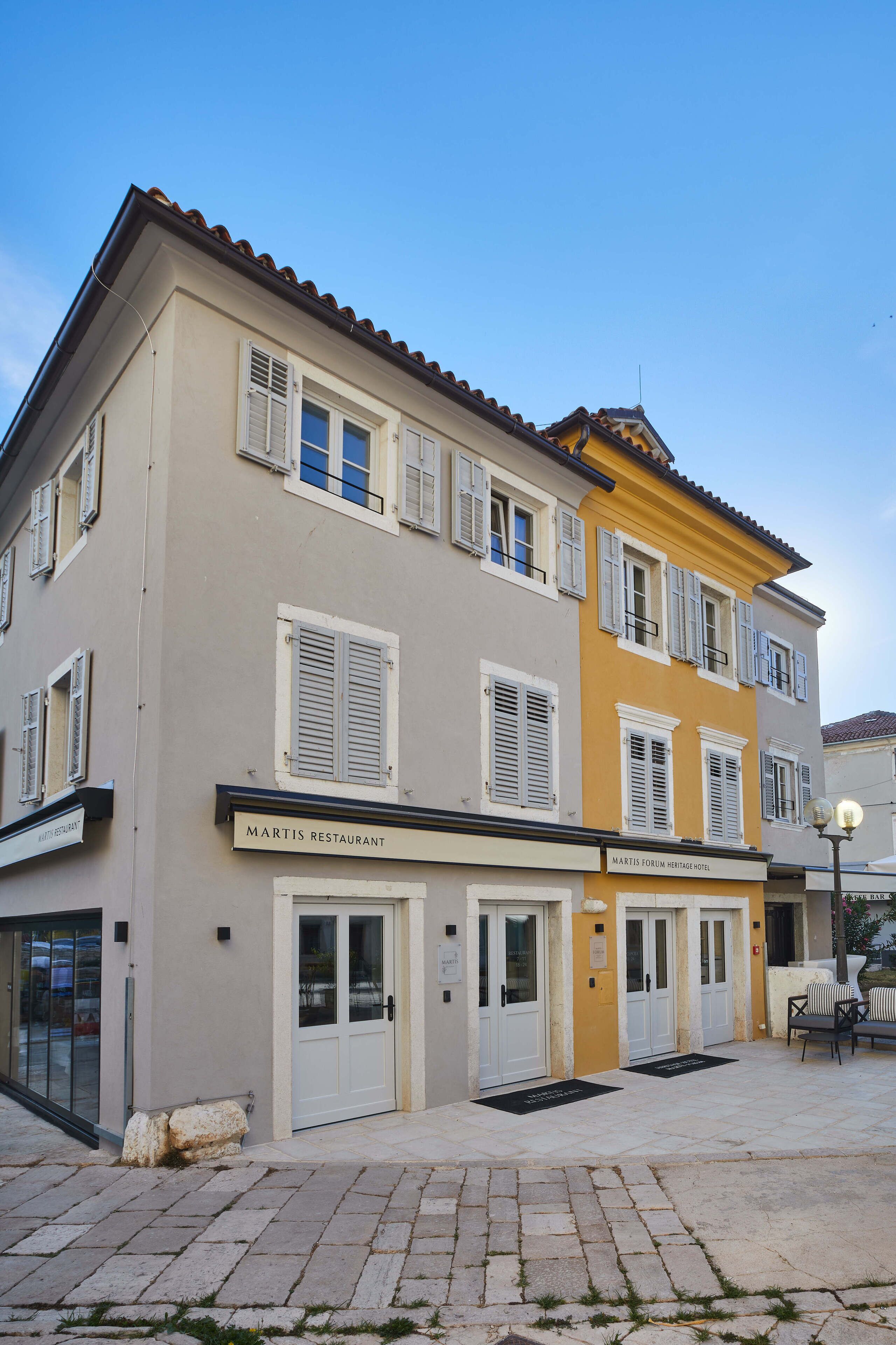 Un edificio de dos pisos con un letrero que dice 'Martis Restaurant' y 'Martis Forum Heritage Hotel'.