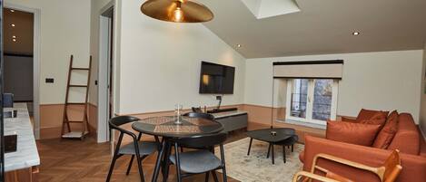 A modern living space with a dining area, a sofa, and a TV.