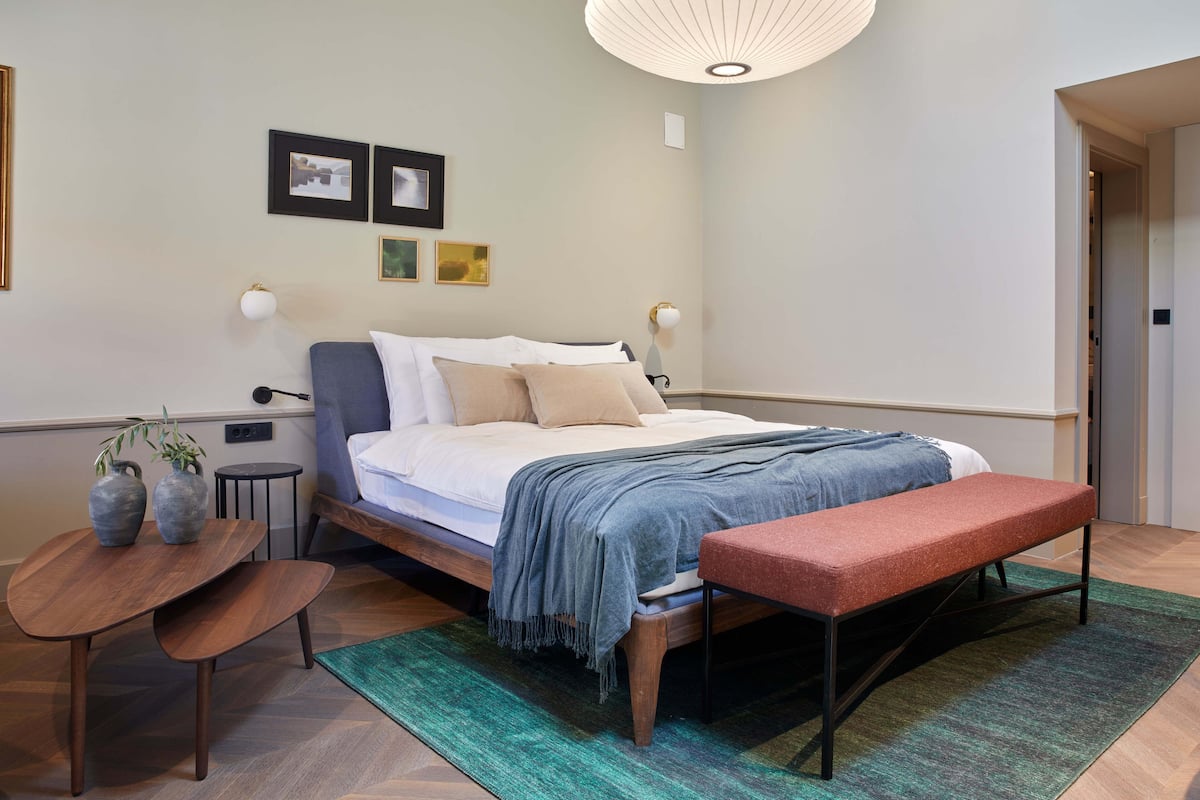 Une chambre à coucher moderne avec un lit, des tables de chevet, un banc et un tapis.