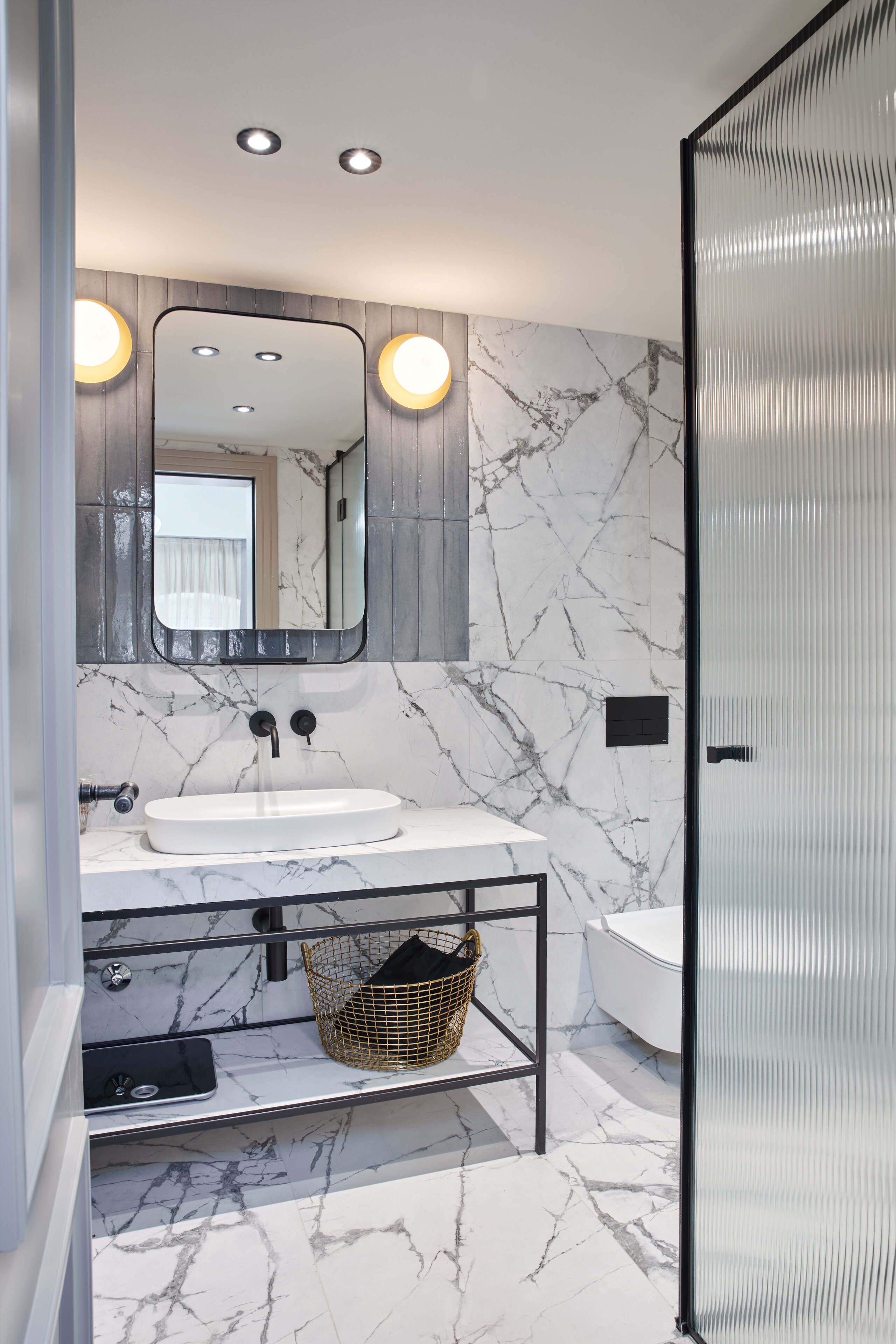 A modern bathroom with a white marble sink, a large mirror, and a glass shower enclosure.