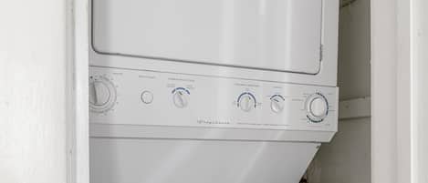 A stacked washer and dryer unit with control knobs and temperature settings.