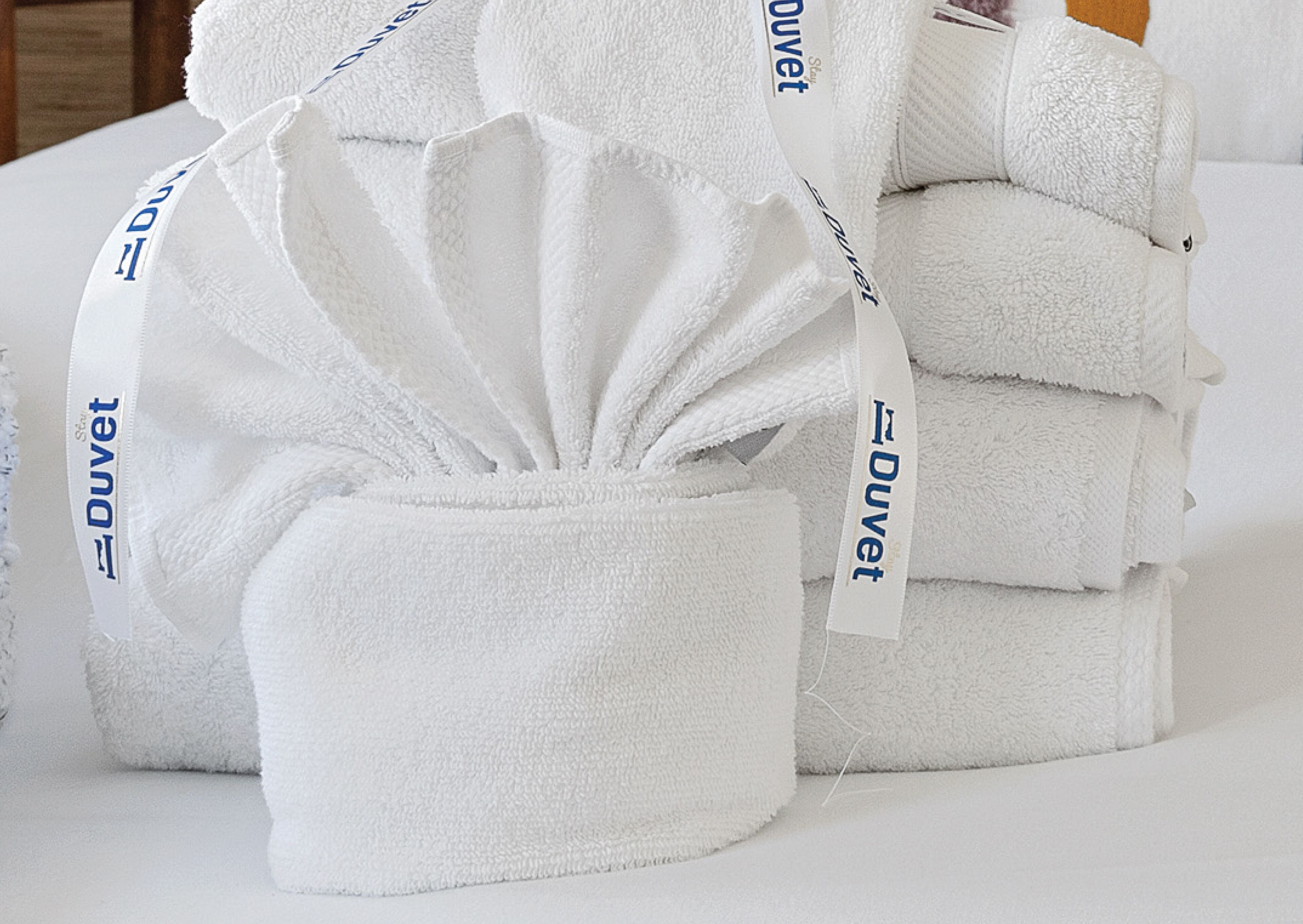 A stack of white towels with 'Duvet' branding.