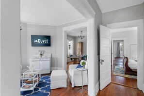 Un salón amplio con un sofá blanco, una mesa de centro y un televisor montado en la pared.