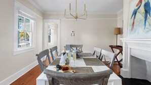 A dining room with a large table, chairs, a chandelier, and a painting on the wall.